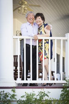 Attractive Happy Chinese Couple Enjoying Their House Outside.