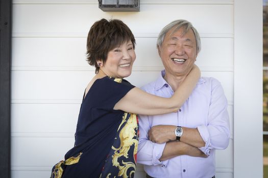 Attractive Happy Chinese Couple Enjoying Their House Outside.