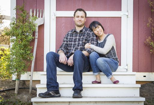 Happy Mixed Race Couple Relaxing on the Steps of Their Barn.