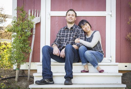 Happy Mixed Race Couple Relaxing on the Steps of Their Barn.