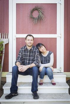 Happy Mixed Race Couple Relaxing on the Steps of Their Barn.