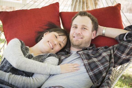 Happy Mixed Race Couple Relaxing in a Hammock Outside.