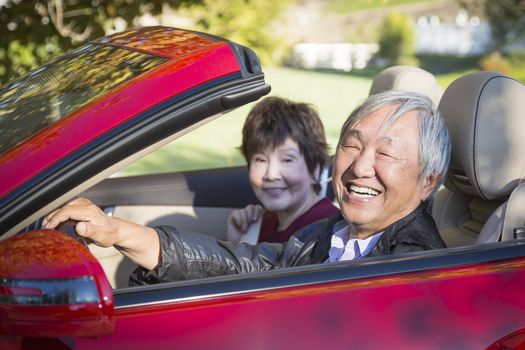 Attractive Happy Chinese Couple Enjoying An Afternoon Drive in Their Convertible.