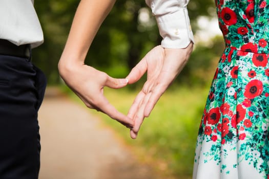 Bride and groom standing together with heart in park