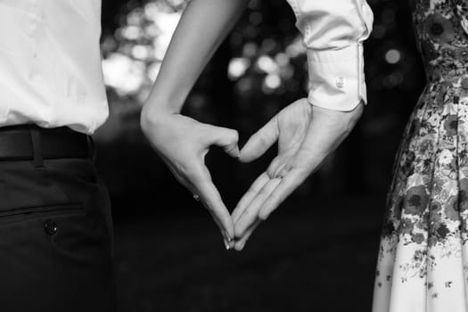 Bride and groom standing together with heart in park