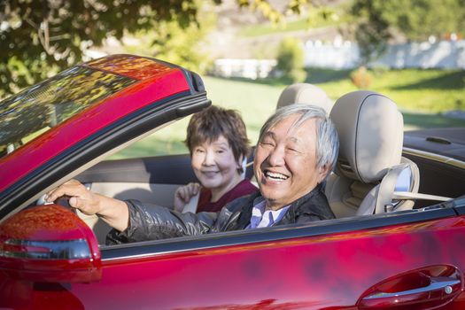 Attractive Happy Chinese Couple Enjoying An Afternoon Drive in Their Convertible.