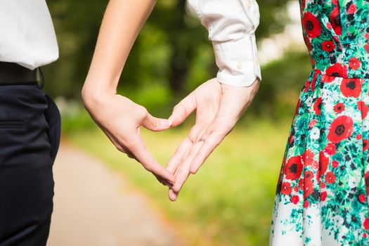 Bride and groom standing together with heart in park