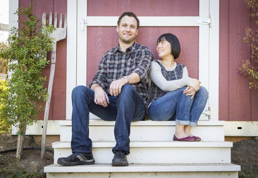 Happy Mixed Race Couple Relaxing on the Steps of Their Barn.