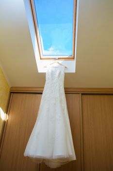 wedding dress hanging on window at hotel room