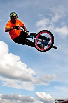 Hampton, GA, USA - September 27, 2014:  A young man with the High Roller BMX club rotates his bike in midair while performing a BMX stunt at the Georgia State Fair.