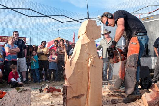 Hampton, GA, USA - September 27, 2014:  A chainsaw sculptor begins carving a dog sculpture out of a huge chunk of wood, at the Georgia State Fair. 
