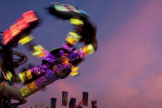 Hampton, GA, USA - September 27, 2014:  The colorful lights of a fast moving carnival ride motion blur against the night sky at the Georgia State Fair. 