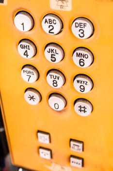 Closeup view of yellow public pay phone keypad