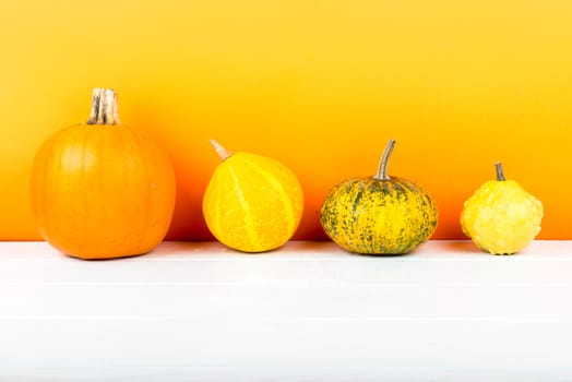 Fresh pumpkins isolated on white wooden table and orange background