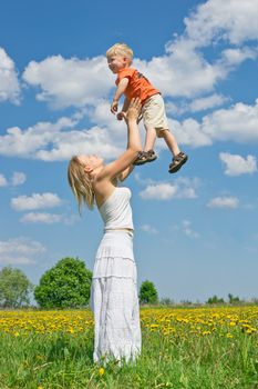 Mother throwing son into the air on meadow