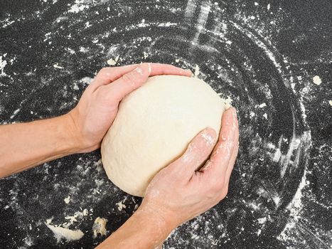 Hands kneading dough on black board