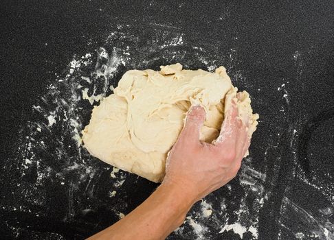 Hands kneading dough on black board