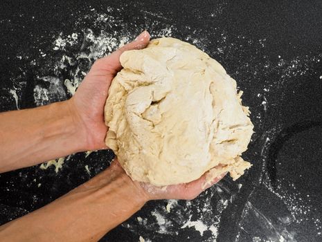 Hands kneading dough on black board