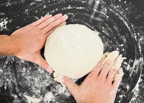 Hands kneading dough on black board