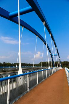 A blue steel structure of a bridge crossing a river