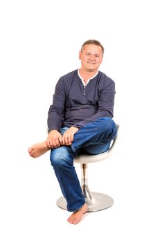 Casually dressed middle aged man smiling. Sitting on chair man shot in vertical format isolated on white.