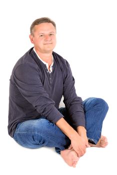 Casually dressed middle aged man smiling. Sitting on a floor man shot in vertical format isolated on white.