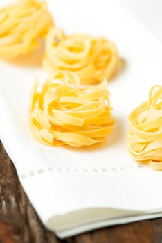 Nests of dry pasta tagliatelle on white table cloth