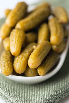 Dill pickles in bowl in soft focus. Macro with shallow dof.