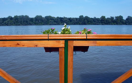 blue river and horizon view from wooden terrace fence with a flower pot