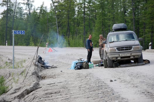 Men and car repair at gravel road Kolyma to Magadan highway at Yakutia, Russia