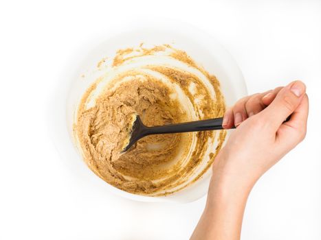 Person siring a bake mix in white plastic bowl with black spatula towards white