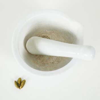 White marble mortar with whole cardamom on the side