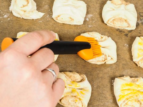 Person glazing plaited baked goods with egg wash