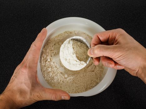 Person using a measurement tool in a bowl of wheat flour