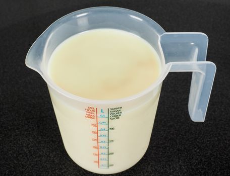 Half a liter of white milk in a transparent measurement plastic mug