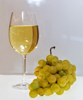 Glass of white wine with a sprig of grapes