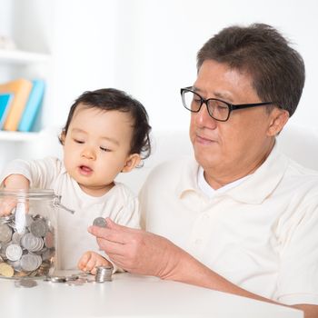 Asian family saving coins indoor, grandpa and grandchild living lifestyle at home.