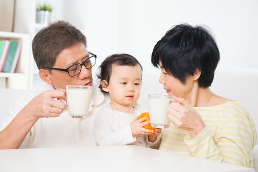 Asian family drinking milk, grandparents and grandchild indoor living lifestyle at home.