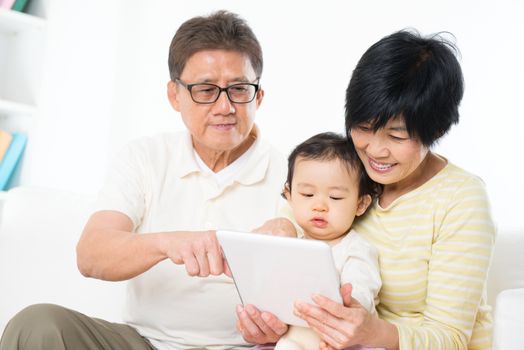 Asian family using digital tablet computer, grandparents and grandchild living lifestyle at home.