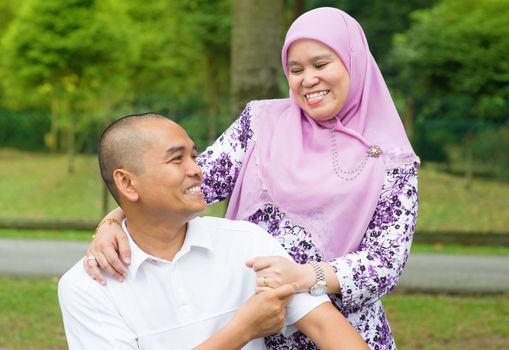 Middle aged Southeast Asian Muslim couple at outdoor park, happy family lifestyle.
