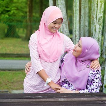 Southeast Asian Muslim mother and daughter at outdoor park, happy family lifestyle.