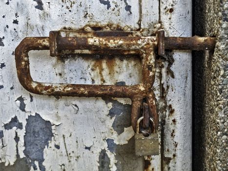 Corroded gate latch with old bronze padlock