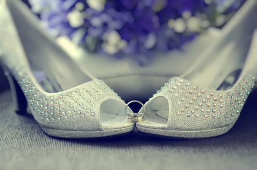 White beaded shoes of bride with wedding rings 