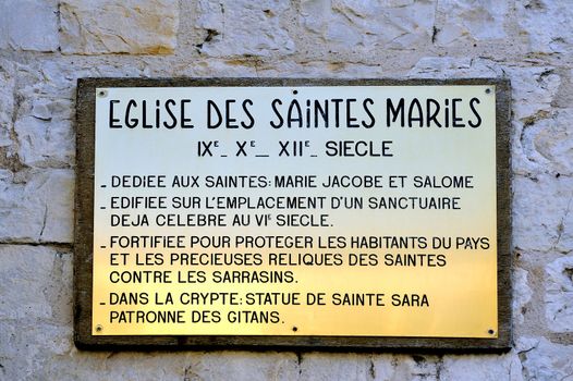 plaque explaining the history of the church of Saintes-Maries-de-la-Mer. Dedicated to Saints Mary Jacobe and Salome and the Crypt containing the statue of Saint Sara patron saint of the Gypsies.