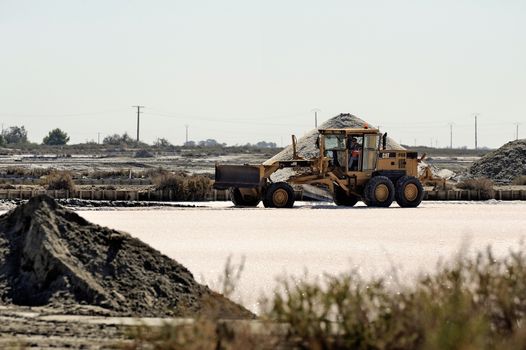 Site operating sea salt saline Aigues-Mortes with big machines and trucks working for the salt storage