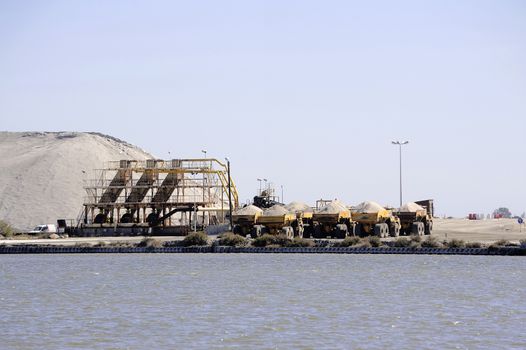 Site operating sea salt saline Aigues-Mortes with big machines and trucks working for the salt storage