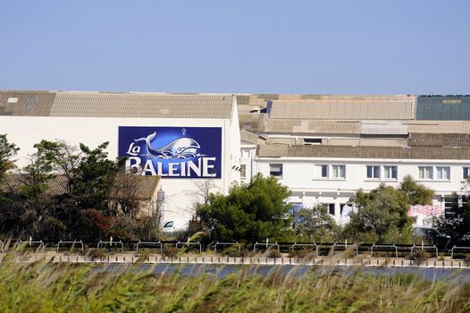 The buildings of the industrial enterprise saline Aigues-Mortes in Camargue with the panel in the name and the logo of the brand.