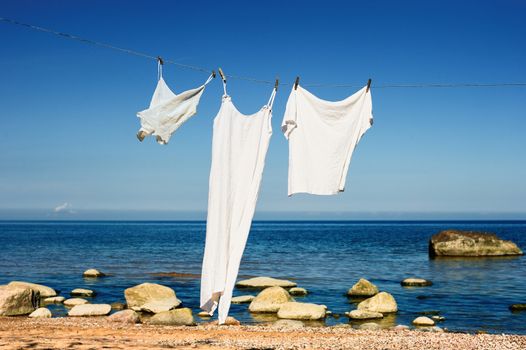 White clothes hanging on a rope on the sea beach