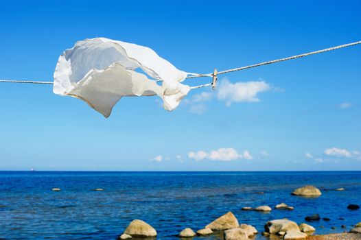 White shirt hanging on a rope on the beach