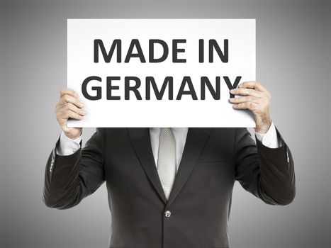 A business man holding a paper in front of his face with the text made in germany